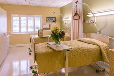 Bright, comfortable resident room with beds and flowers