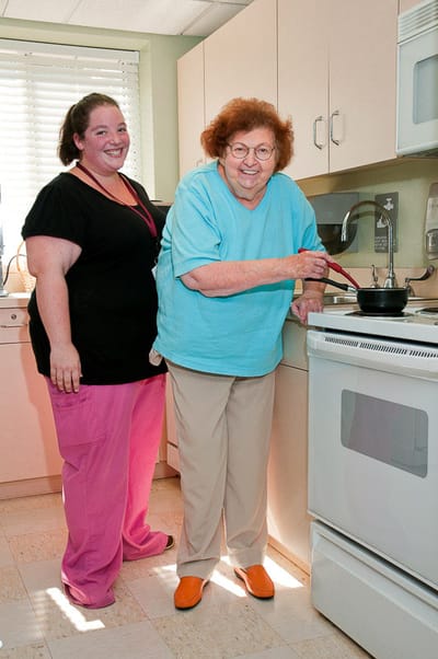 Resident and staff member cooking in the kitchen