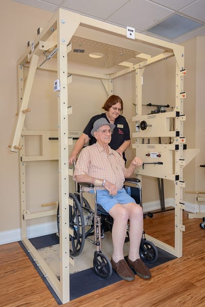 Resident using therapy equipment with staff assistance