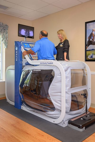 Staff assisting a resident on an anti-gravity treadmill