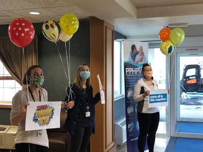 Staff members holding thank you signs in a common area