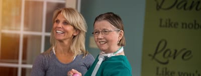 Resident and staff member smiling in an interior setting