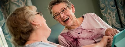 Two residents laughing together in a cozy setting