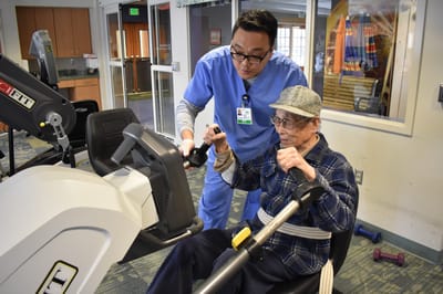 Staff assisting resident with exercise equipment