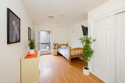 Bright private resident room with a bed and plant