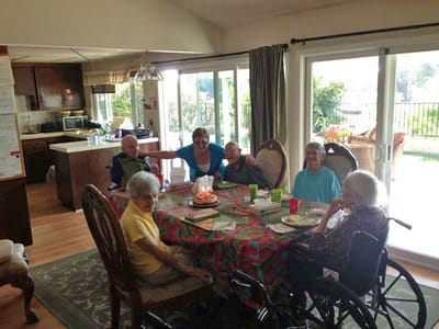Residents and staff celebrating at a table with a cake