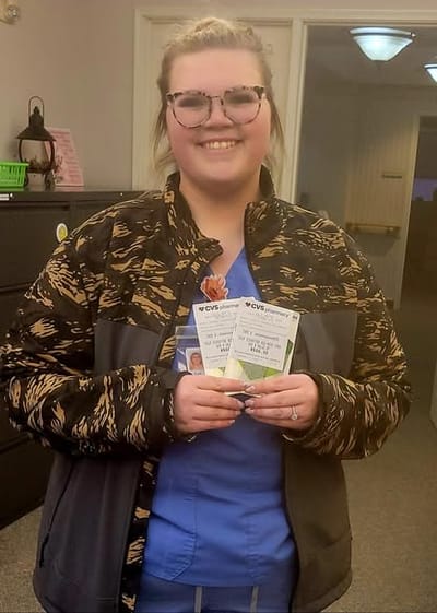 Staff member smiling and holding flyers in an interior space