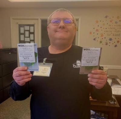 Staff member holding pharmacy cards at reception