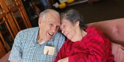 Two smiling residents sharing a joyful moment on a couch