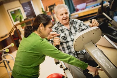 Staff assisting a resident in a therapy exercise