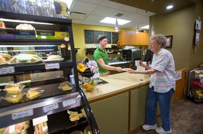A staff member serving food to a resident in the dining area