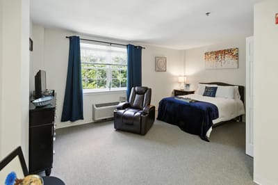 Cozy resident room with a recliner and bed in soft colors