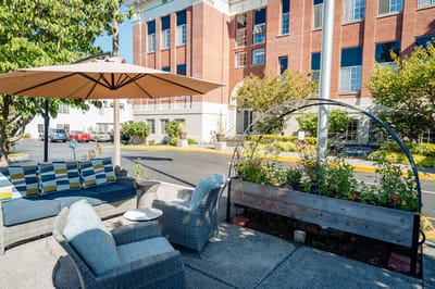Outdoor seating area with garden and building in background