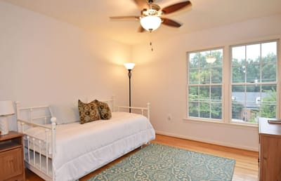 A bright and inviting private room with a daybed and windows