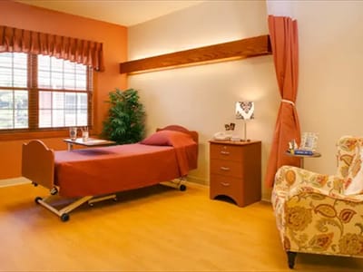 A well-furnished private resident room with a bed and chair