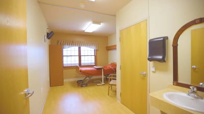 Interior of a private resident room with a bed and chair