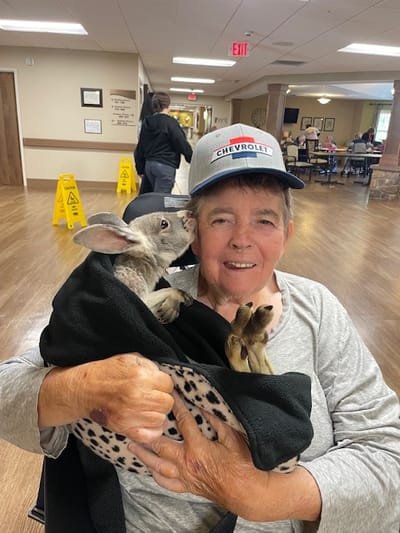 Resident joyfully holding a rabbit in a common area