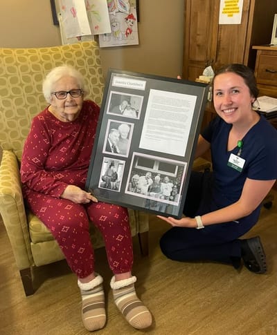 Resident and staff member holding a framed photo display
