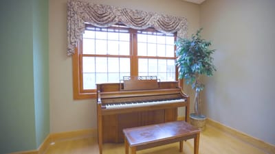 Indoor piano with a bench and natural light