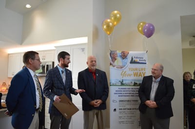 Four men speaking during an indoor event with balloons