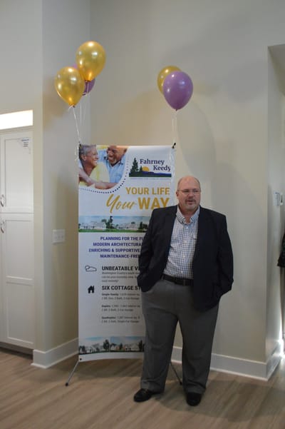 Man standing by a banner with balloons in a facility's interior