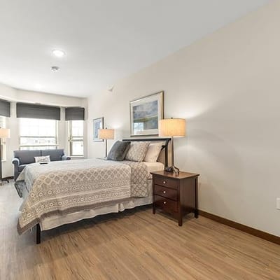 A well-furnished private resident room with a bed and seating area