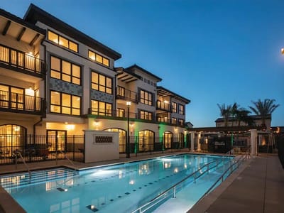 Exterior view of a building with a pool area at twilight