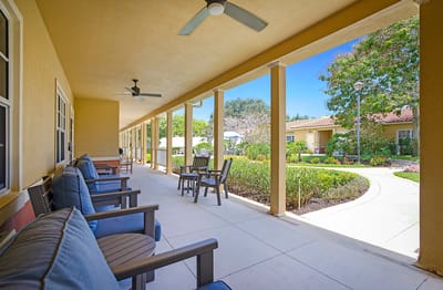 A cozy covered patio area with seating and greenery