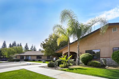Exterior view of a senior living facility with palm trees