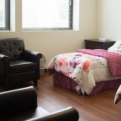 Cozy resident room with a floral comforter and armchair