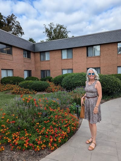 A woman poses in front of the facility's flower garden.