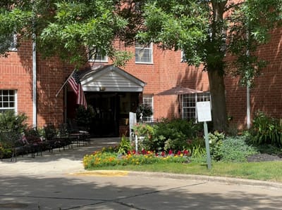 Exterior view of a senior living facility entrance with flowers
