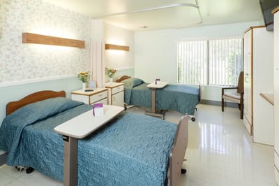 A shared resident room with two beds and bedside tables