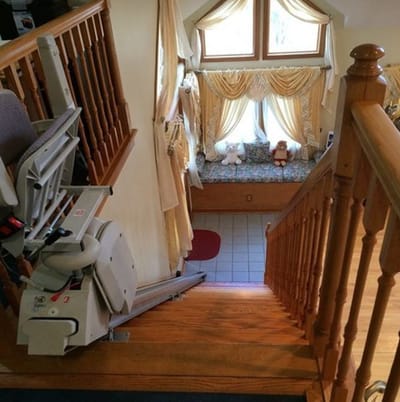 Staircase with a chair lift and plush toys on a window seat