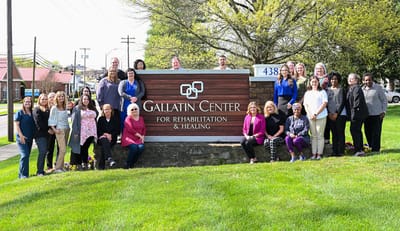 Staff members posing in front of the facility sign