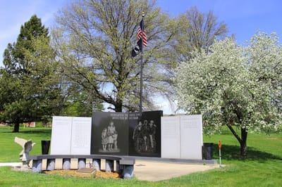 Veterans memorial with flags and flowers in a park setting