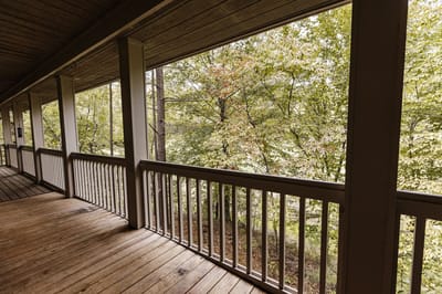 Covered porch with a view of lush trees
