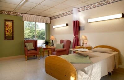 A well-furnished resident room with seating and bedside lamps