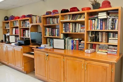 Shelving with books and decorative hats in a common area