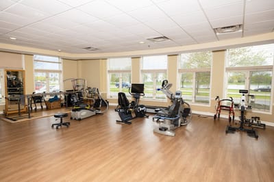 Interior gym area with exercise equipment and large windows