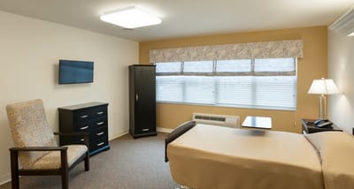 A private resident room with a bed and chair