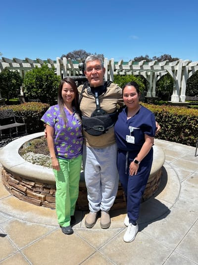 Staff members with a resident in an outdoor garden area