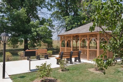 Outdoor gazebo with benches surrounded by greenery