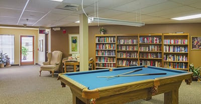 Interior view of a common area with a pool table and bookshelves