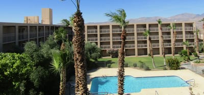 Outdoor pool area with palm trees and building facade