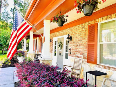 Front entrance of a senior living facility with flowers and flag