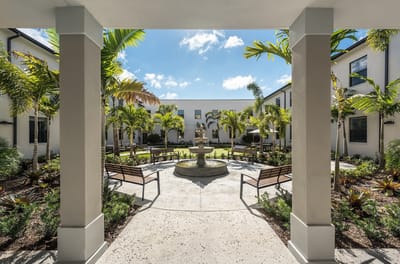 View of a tranquil courtyard with benches and palm trees