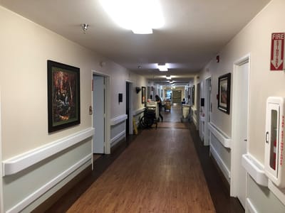 A corridor in a senior care facility with paintings