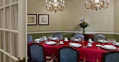 A dining room set up for a meal with a red tablecloth