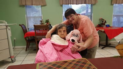 Resident and staff member posing with a plush toy